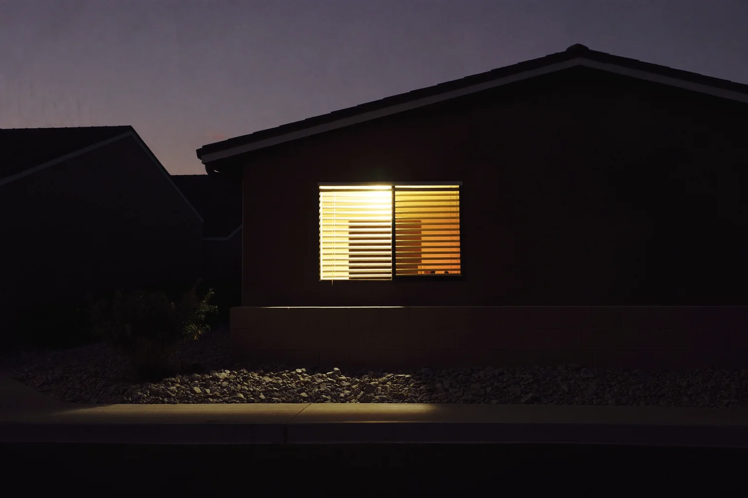Una ventana iluminada con persianas entreabiertas en una calle tranquila de Las Vegas al atardecer